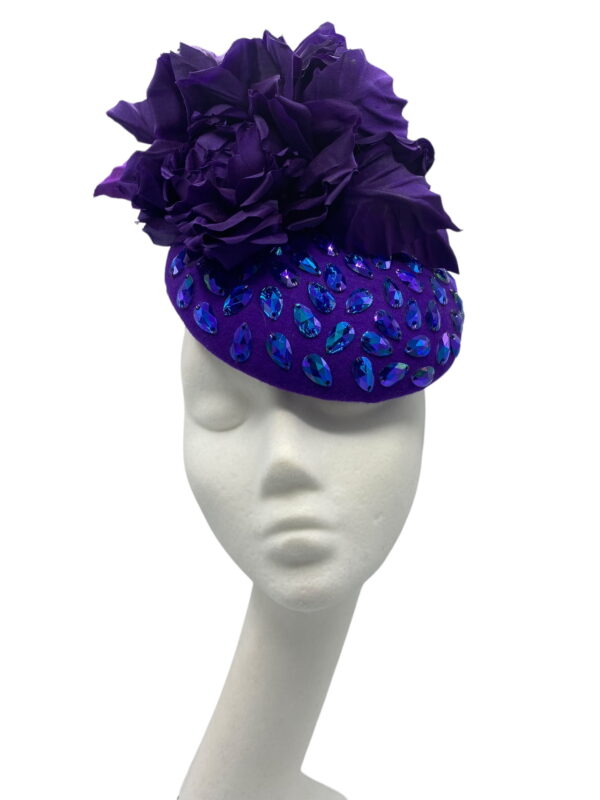 Stunning purple felt base headpiece with irridescent blue embelished detail and finished with stunning hand made silk flower details.